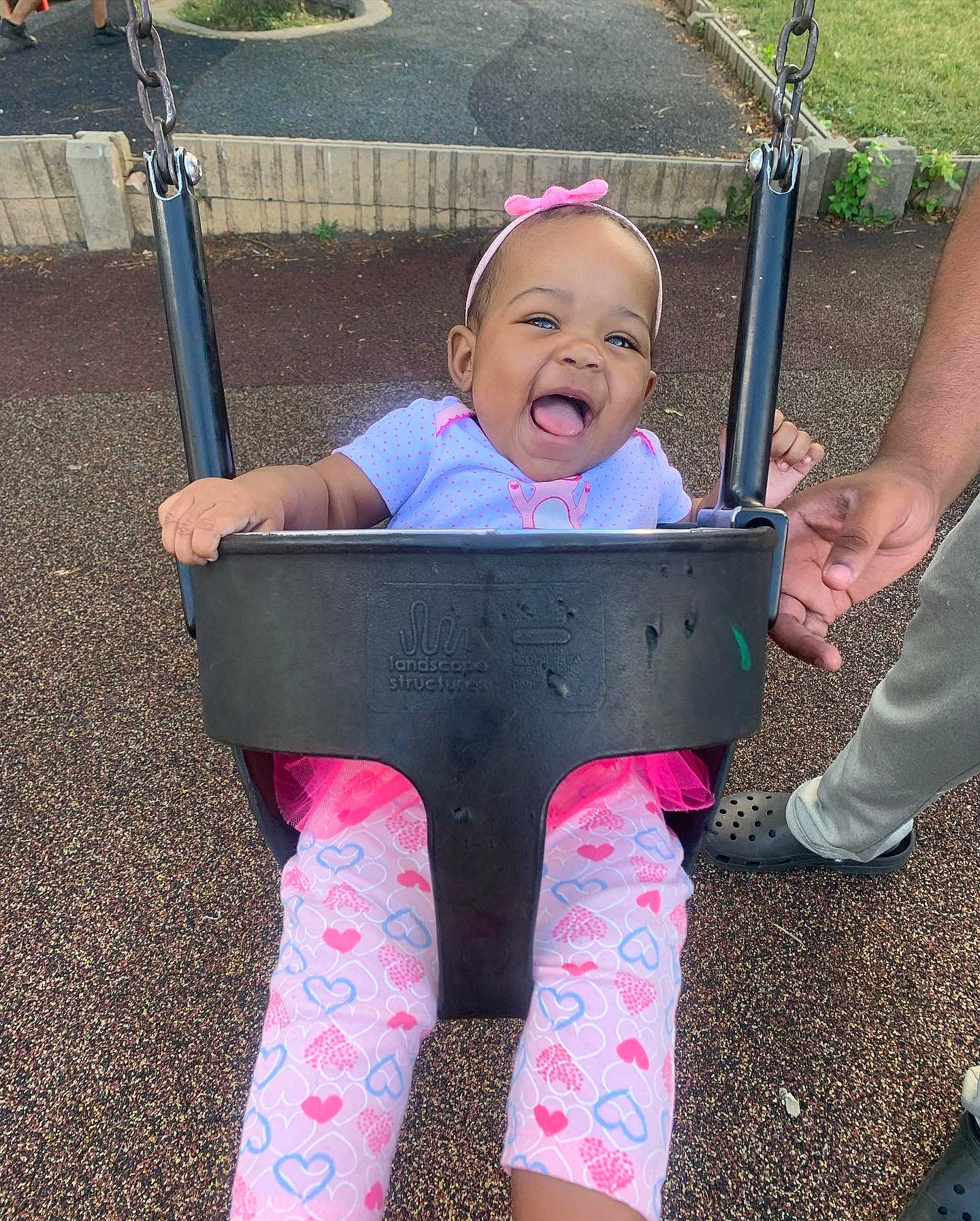 Rylee is registered to the contest to win money with this photo: baby, baby_carriage, baby_toddler_clothing, child, city, face, fun, grass, happy, leisure, person, pink, public_space, purple, recreation, shoe, sleeve, smile, swing, toddler