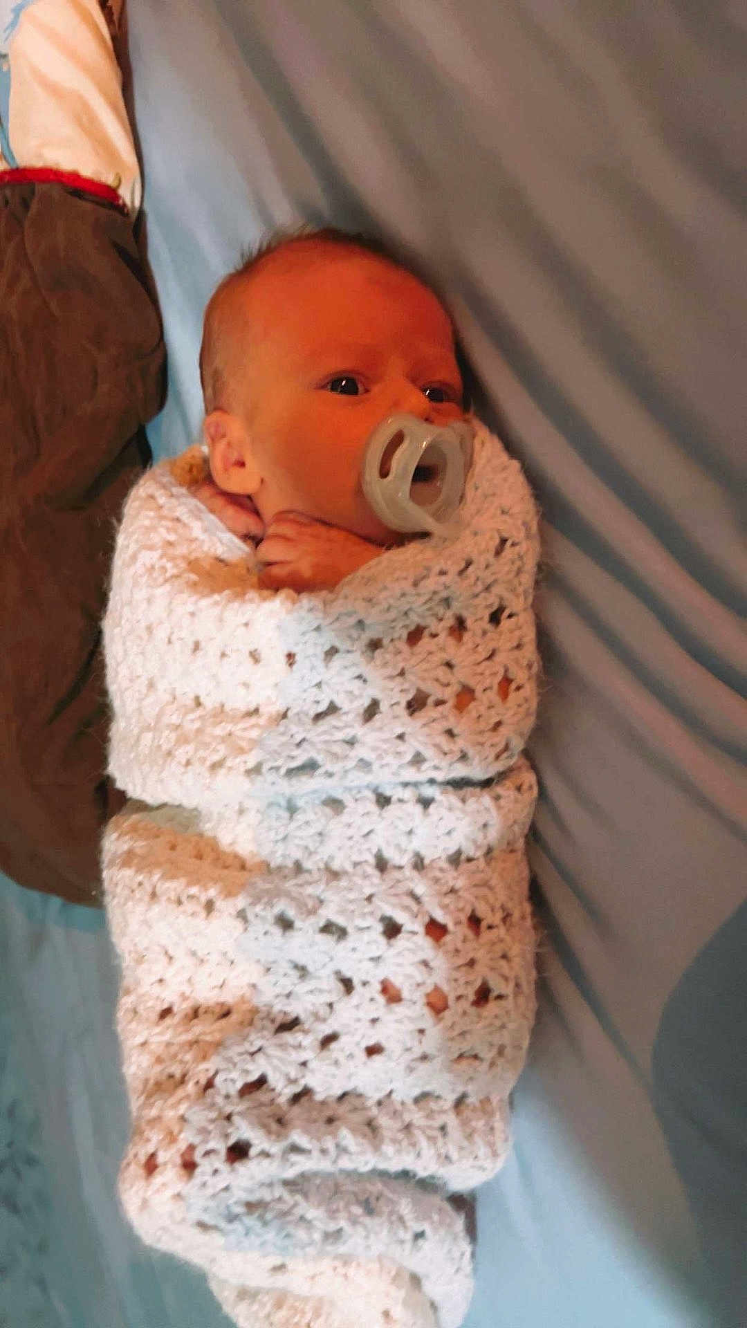 Waylon is registered to the contest to win money with this photo: baby, infant, pacifier, blanket, crochet, wrapped, sleeping, resting, blue_background, brown_cloth, newborn, face, head, cute, soft_texture, indoors, person, comfort, small, peaceful