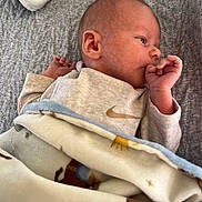 Waylon is registered to the contest to win money with this photo: newborn, baby, infant, blanket, sleepwear, thumb_sucking, face, head, lying_down, cozy, soft_texture, gray_blanket, patterned_blanket, clothing, resting, young_child, indoors, portrait, peaceful, cute
