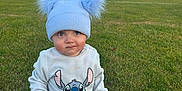 Arlo joined the competition — help win amazing prizes! baby, child, grass, outdoor, blue_hat, pom_poms, sweater, pants, socks, field, sky, sunset, cute, sitting, young_child, stitch_character, clothing, nature, portrait, daylight