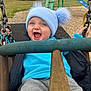 Arlo joined the competition — help win amazing prizes! toddler, child, swing, playground, blue_hat, pom_poms, smiling, happy, outdoor, chains, jacket, sweatshirt, pants, grass, play_equipment, fence, daylight, fun, cute, person