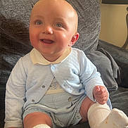 Arlo joined the competition — help win amazing prizes! baby, smiling, child, blue_clothing, socks, couch, indoor, lamp, happy, portrait, sitting, cozy, cute, infant, face, head, skin, furniture, home, light