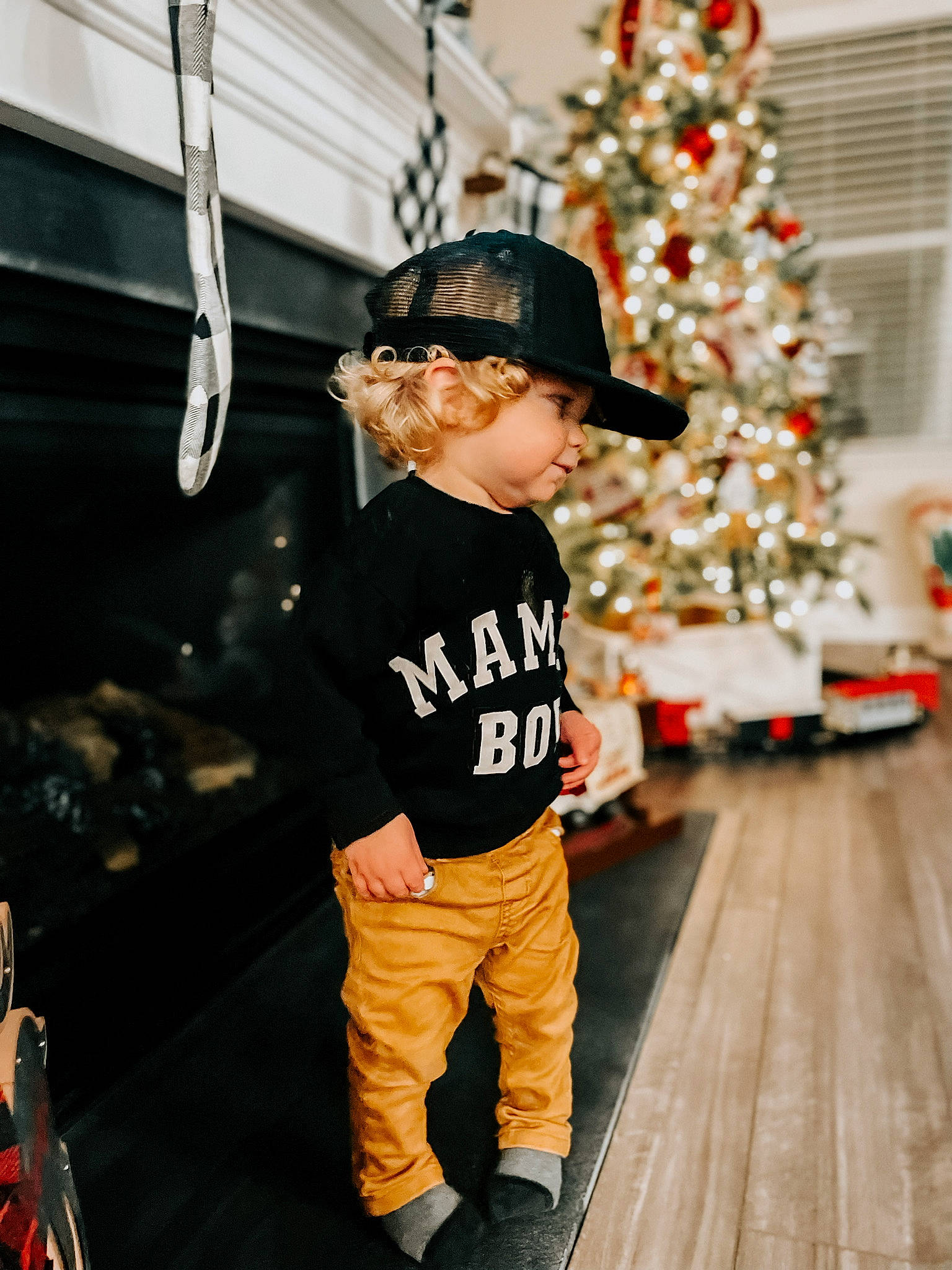 Lander is registered to the contest to win money with this photo: baby_toddler_clothing, baseball_cap, cap, child, christmas, christmas_decoration, christmas_eve, christmas_ornament, christmas_tree, event, flooring, fun, happy, holiday, holiday_ornament, ornament, person, sleeve, standing, toddler