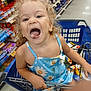 Isabella joined the competition — help win amazing prizes! child, toddler, shopping_cart, blue_dress, curly_hair, grocery_store, aisle, shelf, snacks, happy, smiling, playful, tongue_out, person, retail, shopping, clothing, indoor, fun, cute