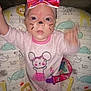 baby, infant, pink_onesie, face_paint, bow_headband, mouse_design, cushion, animal_print, giraffe, lion, whiskers, nose_paint, hand, waving, toy_clip, pacifier_clip, smiling, cute, indoors, child