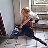 Symba participe au concours pour gagner de l'argent avec cette photo : animal, black_dog, blonde_hair, child, crouching, dog, domestic_scene, entryway, feeding, food_bowl, girl, home, indoors, long_hair, pet, playful, sitting, stairs, tile_floor, water_bowl