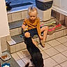 Symba a rejoint le concours — aidez-le/la à gagner de superbes lots ! black_dog, blonde_hair, candid_photo, child, dog, dog_toy, home, indoors, kitchen, long_hair, orange_shirt, pet, pet_bowl, scratching_board, shorts, sitting, stairs, tiled_floor, toddler, trash_bin