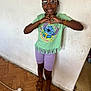 Victoria a rejoint le concours — aidez-le/la à gagner de superbes lots ! child, girl, smiling, glasses, green_tshirt, stitch_character, purple_shorts, brown_sandals, hair_puff, hair_accessory, heart_hands, indoor, wall, wood_floor, power_cord, earrings, bracelet, standing, happy, casual_clothing