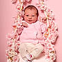 Ava participe au concours pour gagner de l'argent avec cette photo : baby, infant, pink, swing, flowers, cute, child, portrait, knitted_sweater, white_pants, socks, studio, background, flower_garland, smiling, seated, young_child, soft_lighting, indoors, decorative
