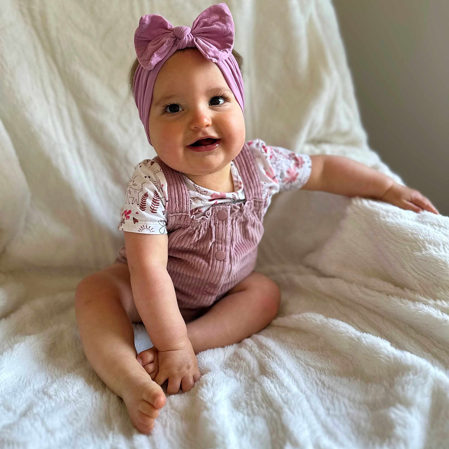 Giulia a rejoint le concours — aidez-le/la à gagner de superbes lots ! baby, blanket, child, clothing, cute, face, happy, headband, indoor, infant, overalls, person, pink_bow, portrait, sitting, skin, smiling, soft_texture, toddler, white_blanket