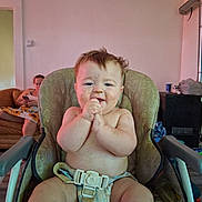 Patrick is registered to the contest to win money with this photo: baby, high_chair, messy, food_smear, clapping, happy, indoor, person, woman, couch, phone, living_room, furniture, diaper, child, smile, seat_belt, home, casual, relaxed