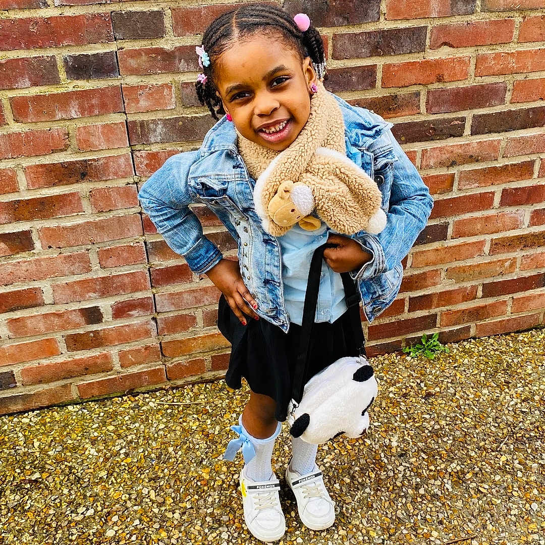 Zoë-Arielle participe au concours pour gagner de l'argent avec cette photo : blackhair, child, clothing, coat, face, female, footwear, girl, hair, happy, head, jacket, jeans, pants, person, photography, portrait, shoe, sitting, sleeve