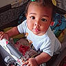 Wynter is registered to the contest to win money with this photo: baby, blanket, child, clothing, colorful, curious, cute, expression, face, hair_clip, hand, indoors, infant, looking_up, person, playpen, soft_toys, toddler, toy, young_child