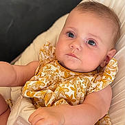 Salomé a rejoint le concours — aidez-le/la à gagner de superbes lots ! baby, infant, child, face, expression, clothing, dress, pattern, floral, yellow, white, seat, cushion, hand, skin, portrait, indoor, cute, young, comfort