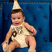 Issaid joined the competition — help win amazing prizes! baby, child, smile, party_hat, socks, blue_chair, happy, infant, cute, celebration, clothing, portrait, sitting, indoor, young_child, face, one_year, furniture, person, candid
