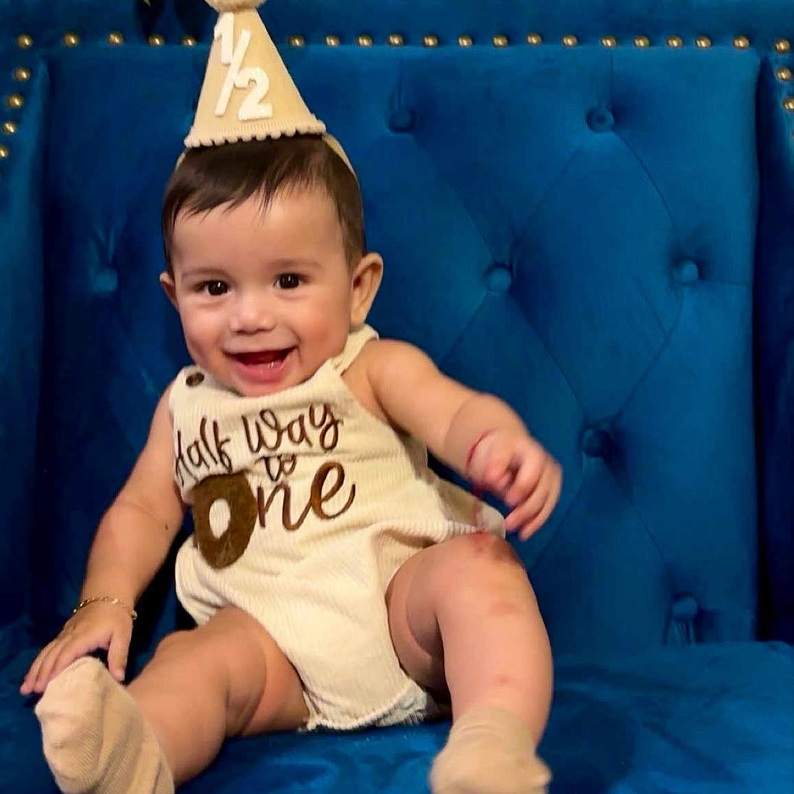 Issaid joined the competition — help win amazing prizes! baby, child, smile, party_hat, socks, blue_chair, happy, infant, cute, celebration, clothing, portrait, sitting, indoor, young_child, face, one_year, furniture, person, candid