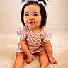 baby, child, infant, smiling, pigtails, purple_bows, pink_dress, sitting, carpet, soft_texture, cute, happy, portrait, indoors, young_child, playful, adorable, face, hands, feet