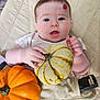 Lilly is registered to the contest to win money with this photo: baby, infant, pumpkin, orange_pumpkin, white_pumpkin, quilted_seat, beige, cute, child, face, hand, holding, autumn, fall, fruit, closeup, expression, indoor, person, soft_light