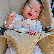 Lilly is registered to the contest to win money with this photo: baby, infant, smile, onesie, animal_print, baby_seat, beige, padded, red_mark, happy, child, indoor, face, hand, clothing, seatbelt, comfort, portrait, young_child, cute