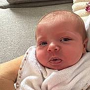 Jeanne a rejoint le concours — aidez-le/la à gagner de superbes lots ! baby, newborn, infant, face, hand, bib, clothing, person, couch, fabric, skin, closeup, indoor, soft, comfort, cute, expression, resting, arm, young