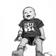 Lily joined the competition — help win amazing prizes! baby, infant, smiling, tshirt, beads, necklaces, legs, feet, happy, portrait, child, black_and_white, studio, joyful, cute, sitting, celebration, party, fun, isolated