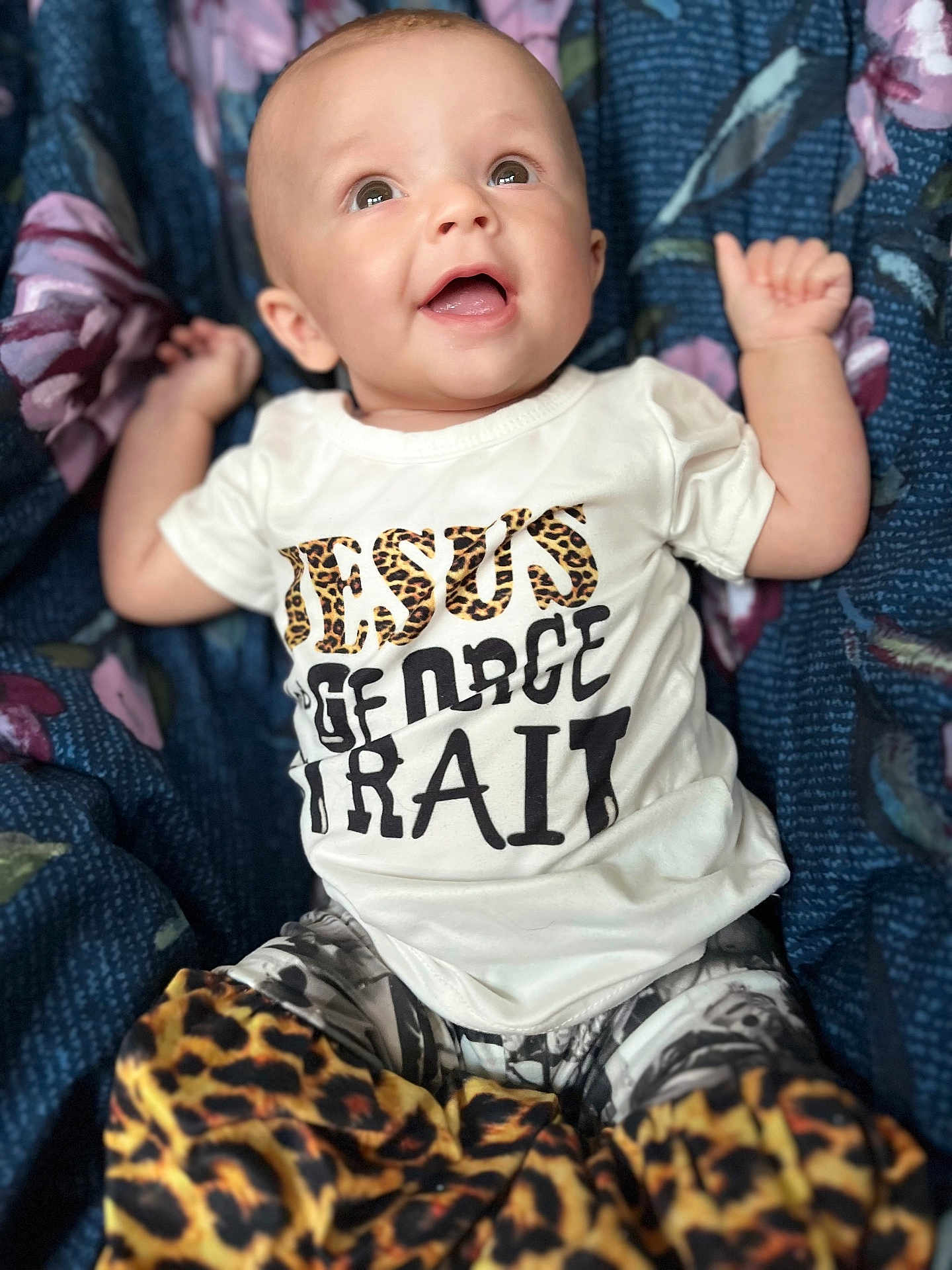 Lily joined the competition — help win amazing prizes! baby, infant, smiling, clothing, shirt, pants, leopard_print, blanket, floral_pattern, happy, portrait, cute, child, person, lying_down, bright_eyes, casual_wear, infant_fashion, indoors, closeup