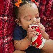 Solana joined the competition — help win amazing prizes! baby, child, infant, sock, red_blanket, hair_bow, cute, chewing, hand, foot, clothing, plush, comfort, indoors, person, skin, head, face, sitting, cozy