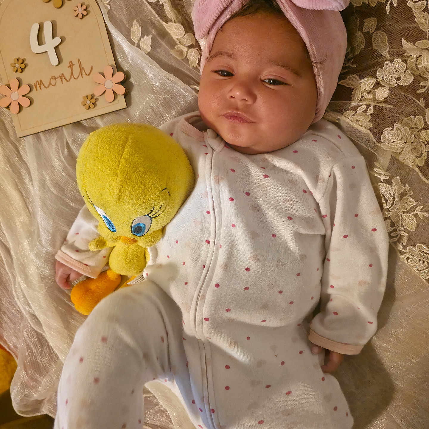 Leilani is registered to the contest to win money with this photo: baby, infant, child, portrait, lying_down, pink_bow, headband, onesie, polka_dots, plush_toy, yellow_toy, stuffed_animal, milestone_sign, four_months, lace, blanket, bedding, indoor, cute, cozy