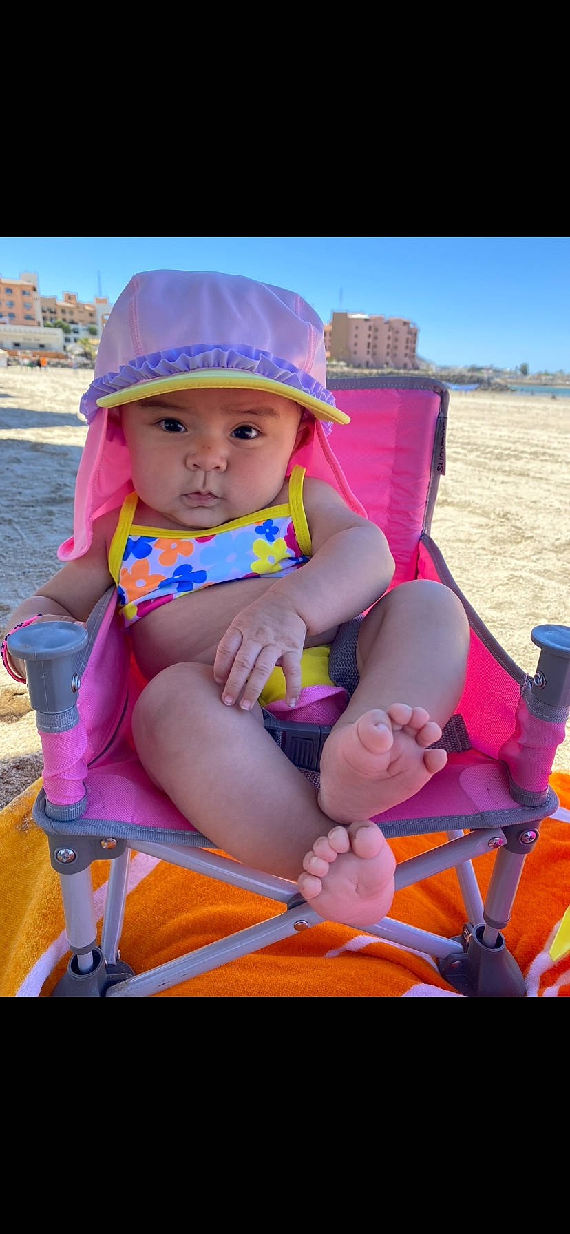 Aaylah is registered to the contest to win money with this photo: baby, baby_toddler_clothing, beach, blue, electric_blue, fun, happy, hat, headwear, leisure, magenta, orange, person, personal_protective_equipment, pink, recreation, sand, sitting, sky, sun_hat
