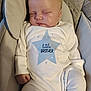 baby, sleeping, infant, onesie, blue_star, little_brother, cushioned_seat, neutral_colors, peaceful, child, face, hand, cute, soft_fabric, newborn, indoor, portrait, resting, cozy, small_fingers