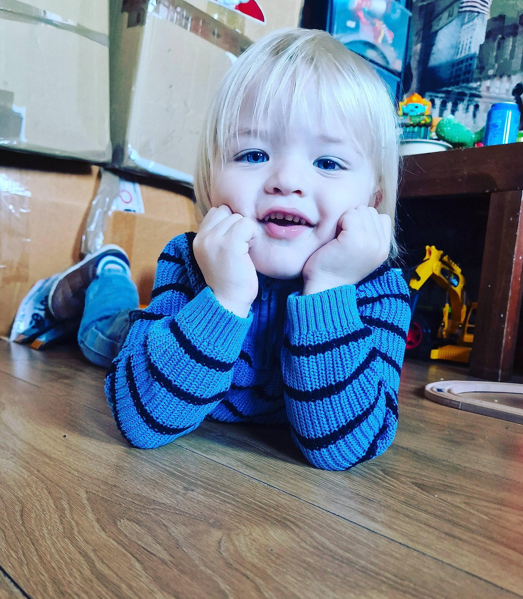 Jaxson is registered to the contest to win money with this photo: baby, baby_toddler_clothing, blue, child, electric_blue, fashion_accessory, floor, flooring, happy, hardwood, nail, pattern, person, shelf, sitting, sleeve, smile, t_shirt, thumb, toddler