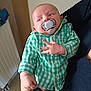 Jules a rejoint le concours — aidez-le/la à gagner de superbes lots ! baby, infant, pacifier, checkered_shirt, green_shirt, hand, arm, being_held, adult_hand, indoor, radiator, tiled_floor, portrait, closeup, cheeks, ears, button_up_shirt, jeans, sideways_gaze, cute