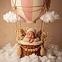 baby, sleeping, knitted_hat, bear_ears, teddy_bears, hot_air_balloon, basket, clouds, soft_lighting, cozy, cute, infant, portrait, props, decorative_lights, woven_basket, child, newborn, studio_photo, neutral_background