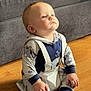 baby, child, infant, sitting, floor, wooden_floor, couch, clothing, koala_print, hoodie, socks, home, indoors, cute, portrait, person, young_child, light, soft_light, thoughtful