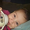 Aryya is registered to the contest to win money with this photo: baby, infant, bottle, feeding, milk, sleepy, lying_down, face, eyes, curious, indoors, blanket, bed, pink_clothing, hand, gripping, portrait, close_up, timestamp, cozy