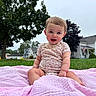 Lillith is registered to the contest to win money with this photo: baby, child, toddler, smiling, sitting, outdoor, portrait, lawn, grass, blanket, pink_blanket, floral_clothing, house, suburban, trees, nature, american_flag, daylight, happy, face