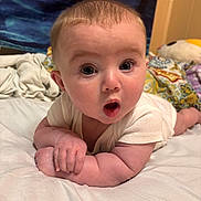 Lillith joined the competition — help win amazing prizes! baby, infant, child, tummy, surprised_expression, wide_eyes, skin, hand, white_clothing, blanket, bed, soft_surface, indoors, cute, portrait, face, head, resting, colorful, expression