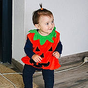Liv a rejoint le concours — aidez-le/la à gagner de superbes lots ! toddler, child, pumpkin_costume, orange, green, black, smile, indoor, floor, wooden_floor, hair_tie, standing, cute, costume, holiday, happy, person, clothing, playful, young_child
