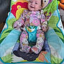 baby, infant, smiling, floral_clothing, baby_bouncer, colorful, indoor, wooden_floor, toy, playful, happy, child, seat, fabric, pattern, cute, person, young_child, comfort, portrait