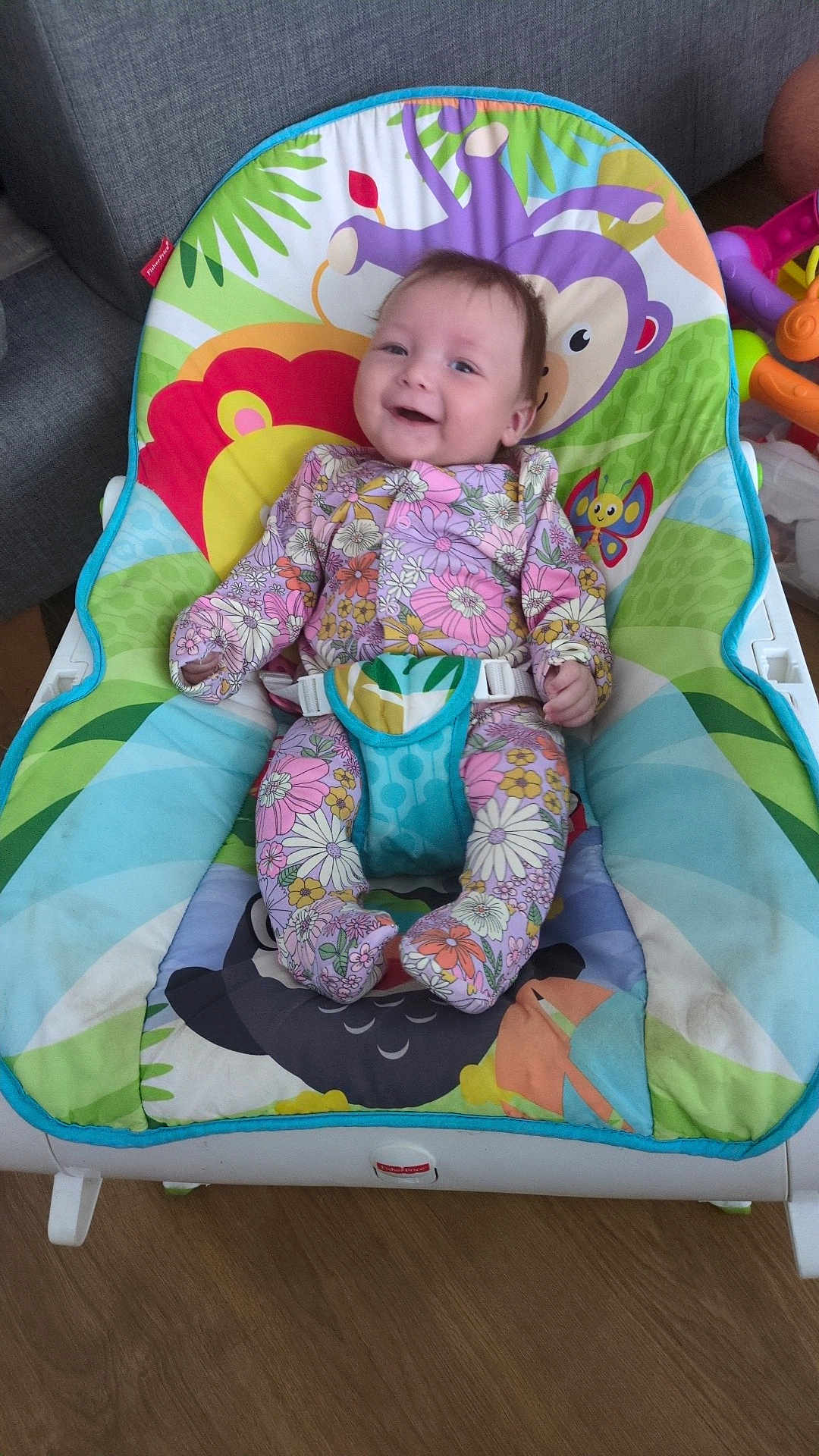 Amelie joined the competition — help win amazing prizes! baby, infant, smiling, floral_clothing, baby_bouncer, colorful, indoor, wooden_floor, toy, playful, happy, child, seat, fabric, pattern, cute, person, young_child, comfort, portrait