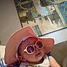 baby, sunglasses, hat, indoor, bib, smiling, child, face, person, colorful, fashion, cute, portrait, accessory, happy, clothing, sitting, hand, couch, artwork