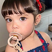 Georgina joined the competition — help win amazing prizes! toddler, child, pacifier, brown_eyes, red_bow, blue_dress, indoor, close_up, cute, young_child, face, portrait, person, hair, skin, expression, baby, clothing, accessory, curious