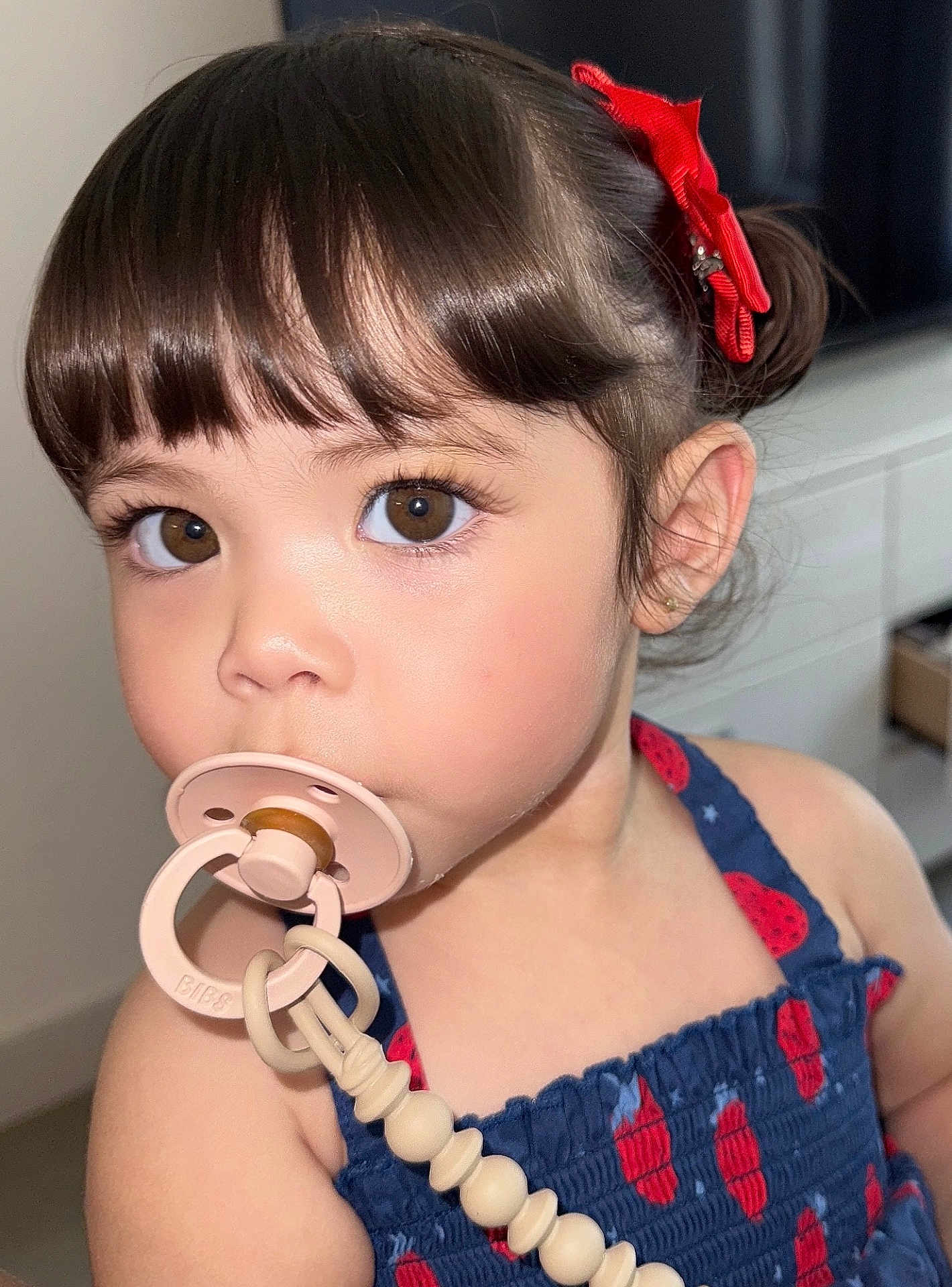 Georgina joined the competition — help win amazing prizes! toddler, child, pacifier, brown_eyes, red_bow, blue_dress, indoor, close_up, cute, young_child, face, portrait, person, hair, skin, expression, baby, clothing, accessory, curious