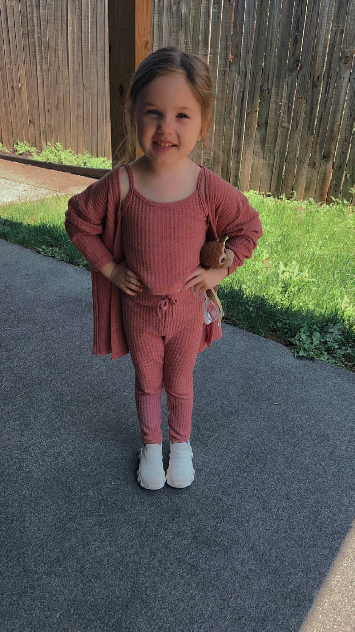 Penelope is registered to the contest to win money with this photo: asphalt, baby, baby_toddler_clothing, child, dress, face, grass, joy, magenta, outerwear, pattern, person, pink, plant, recreation, road_surface, sitting, sleeve, smile, thumb
