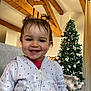 child, christmas_tree, clothing, couch, cozy, curtain, face, happy, holiday, home_decor, hoodie, indoor, living_room, ornaments, person, pigtails, portrait, smile, toddler, wooden_beams