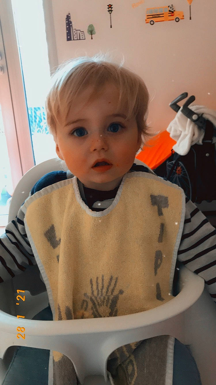 Mathéo participe au concours pour gagner de l'argent avec cette photo : baby, baby_toddler_clothing, bib, chair, cheek, child, drinkware, eyebrow, finger, fun, iris, nose, person, personal_protective_equipment, room, sitting, skin, sleeve, surprise, t_shirt