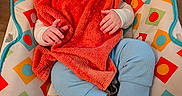 Jaxtyn is registered to the contest to win money with this photo: baby, child, smile, orange_towel, blue_pants, barefoot, cushion, patterned_fabric, indoor, happy, seated, infant, colorful, face, hand, foot, wooden_floor, cute, portrait, cozy