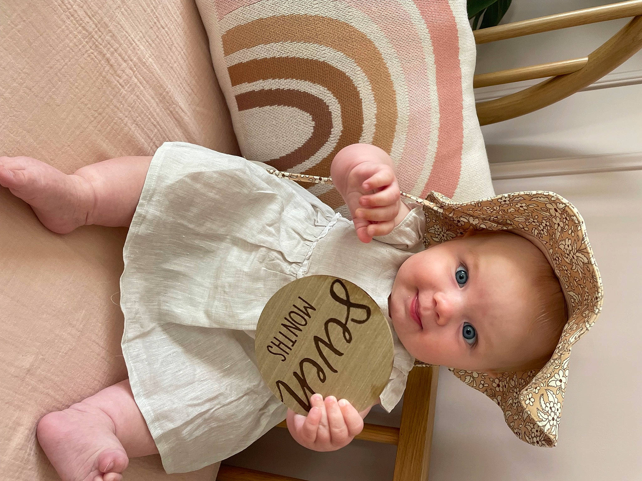 Lennon is registered to the contest to win money with this photo: baby, baby_products, baby_toddler_clothing, beige, child, comfort, face, fashion_accessory, finger, gesture, happy, hat, nail, pattern, person, skin, sleeve, smile, sun_hat, thumb