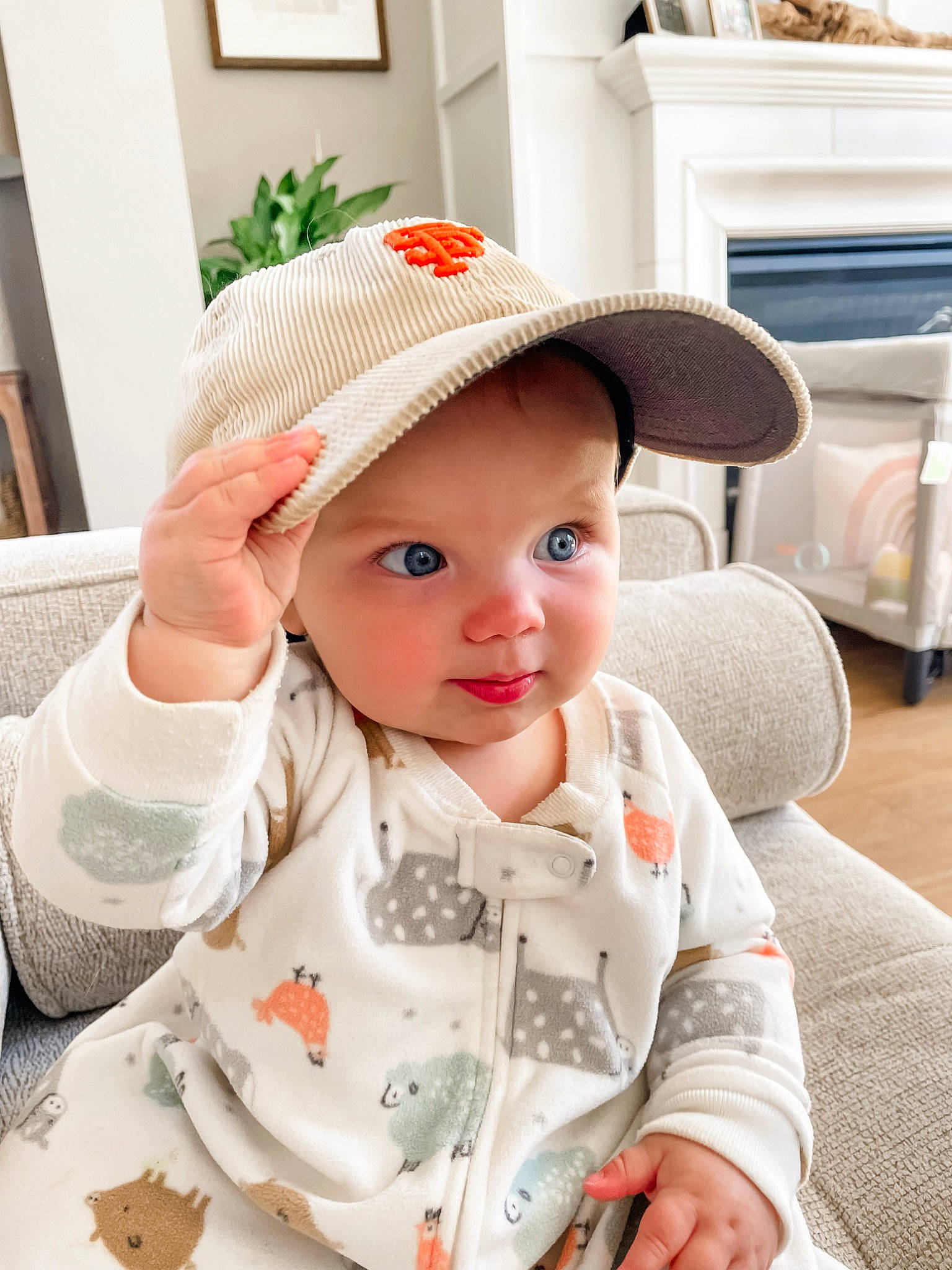 Lennon is registered to the contest to win money with this photo: baby, baby_products, baby_toddler_clothing, cap, cheek, child, collar, comfort, face, facial_expression, fashion_accessory, headwear, lip, pattern, person, plant, product, sitting, skin, sleeve
