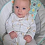 Louie is registered to the contest to win money with this photo: baby, infant, child, onesie, giraffe_pattern, blue_eyes, hands, face, seated, baby_cushion, soft_toys, cozy, patterned, white_clothing, cute, indoors, portrait, young_child, comfort, pink_skin